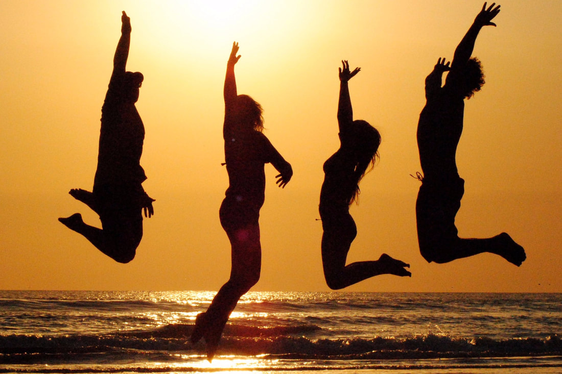 Coaching Group Jumping for Joy on the Beach at Sunset